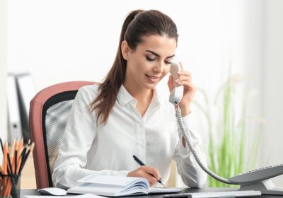 Businesswoman talking on a VoIP desk phone in an office