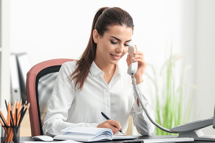 Businesswoman talking on a VoIP desk phone in an office