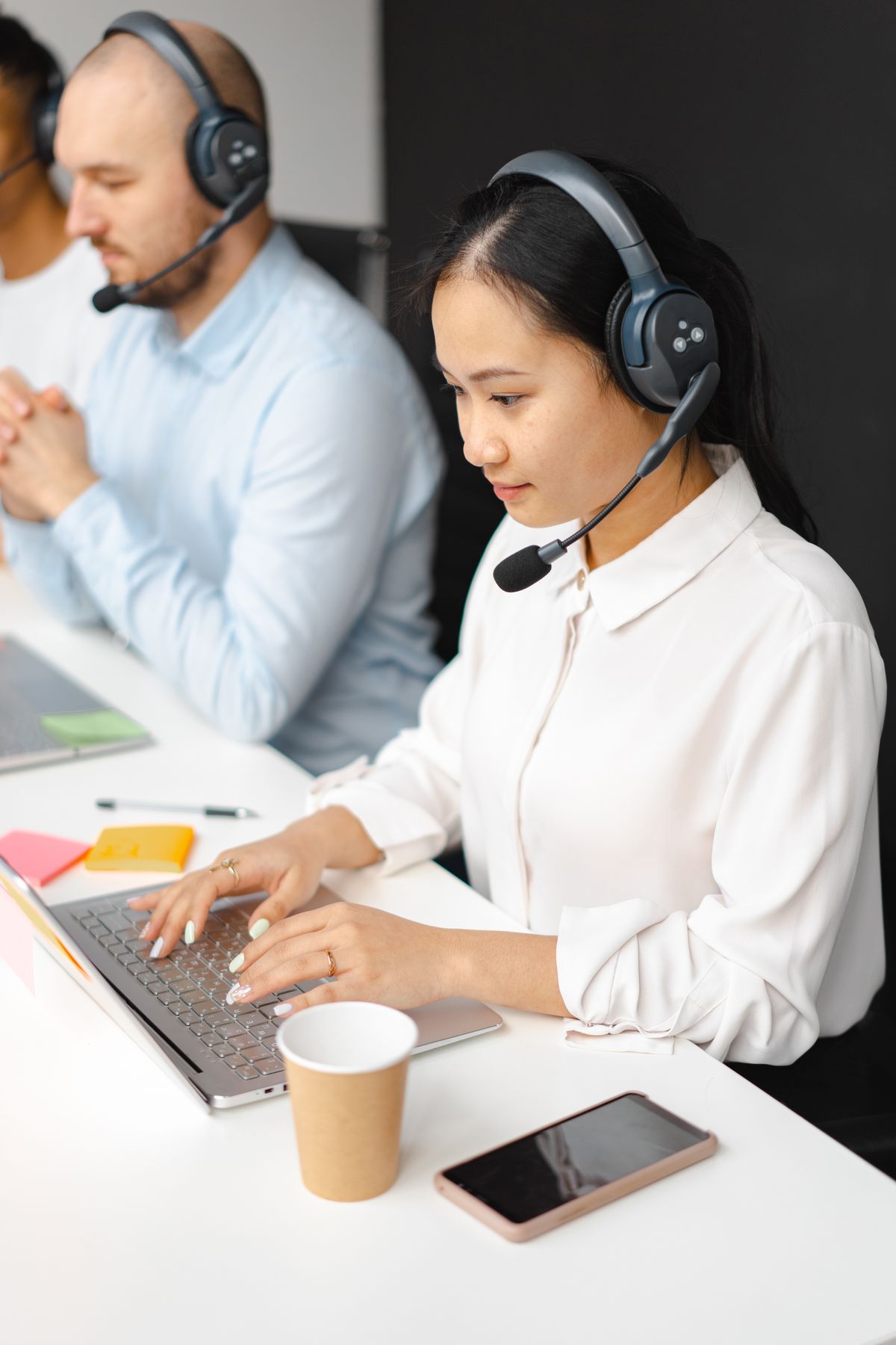 Customer service representatives wearing headsets at their desks
